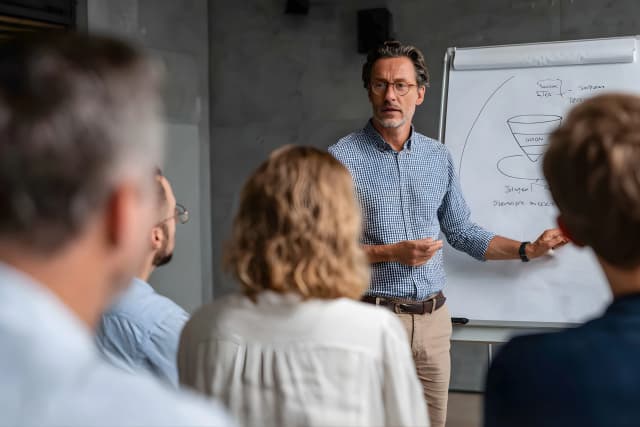 Instructor explaining a digital marketing funnel strategy to a group using a whiteboard.