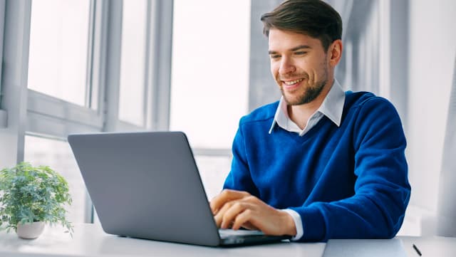 Professional working confidently on a laptop in a bright office environment.